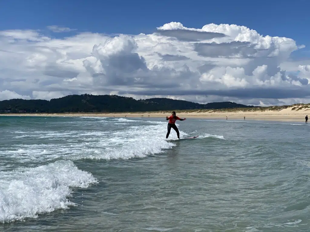 chica en una tabla de surf encima de una pequeña ola